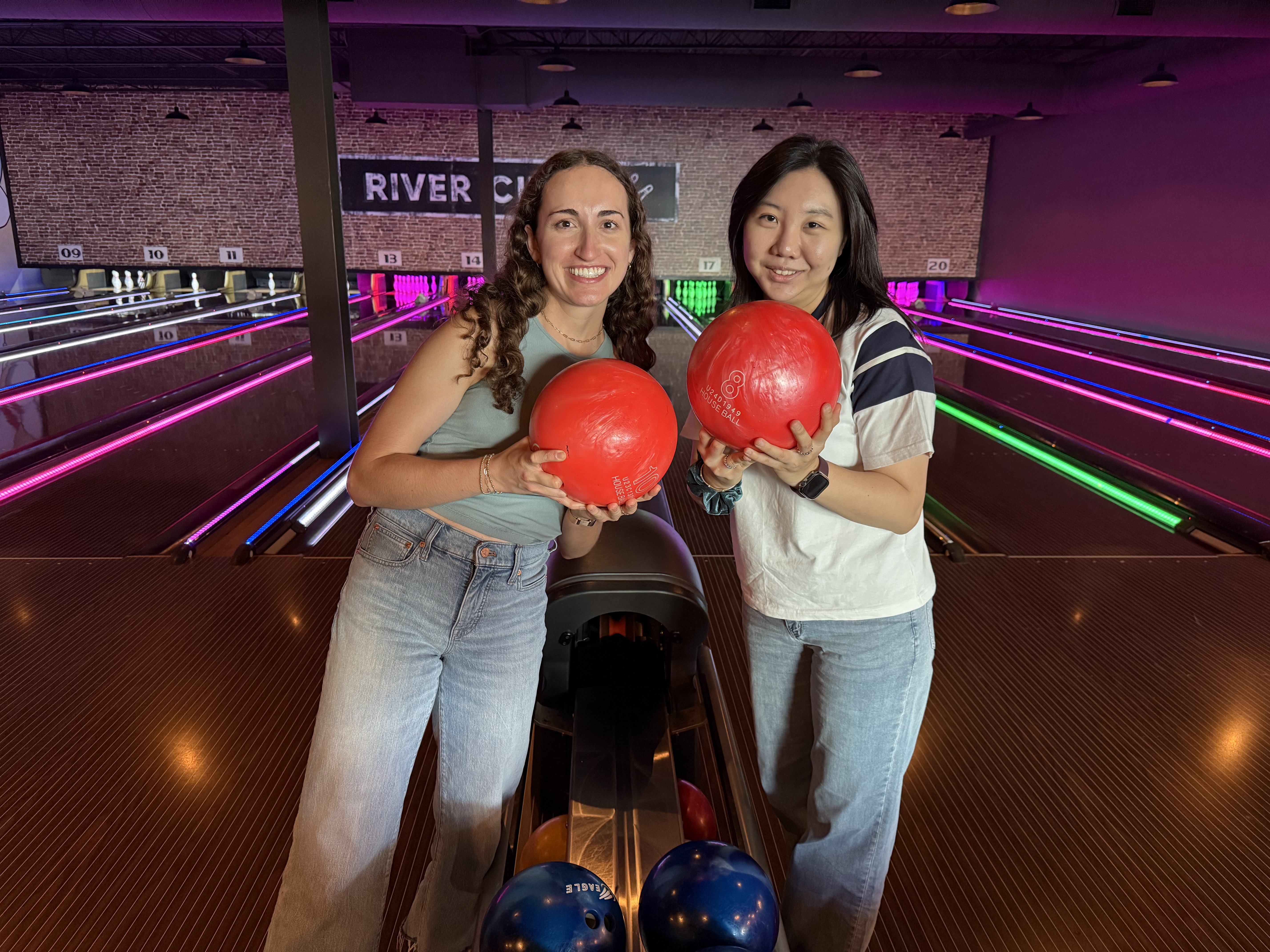Residents Caroline Doherty and Alexis Kim pose with bowling balls at River City Roll