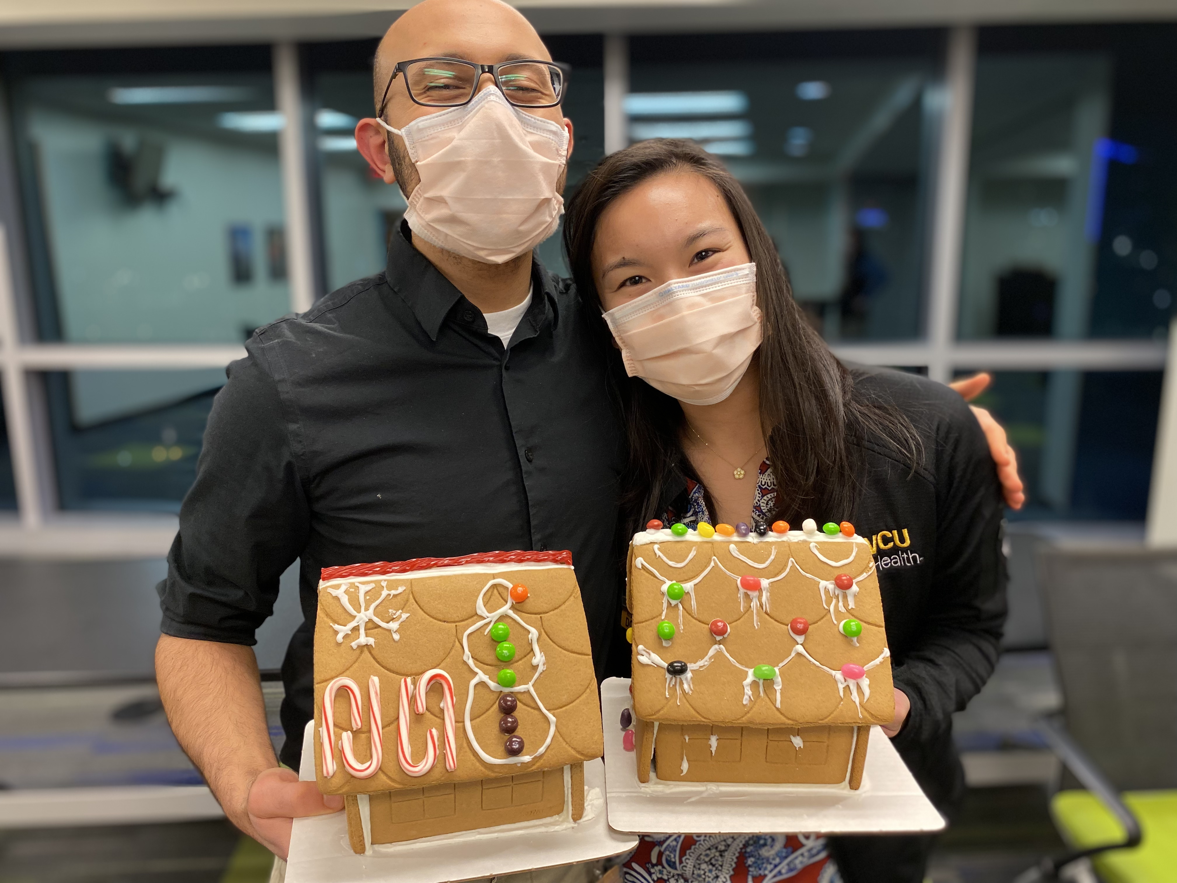 Two residents display the gingerbread houses they decorated at a wellness event